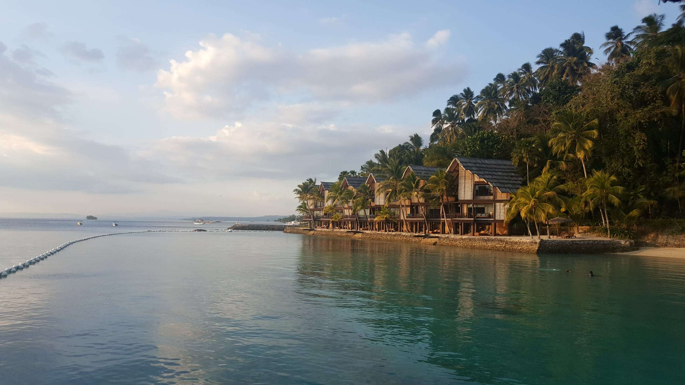 Wooden stilt houses over the water at Pearl Farm Beach Resort on Samal Island at dusk