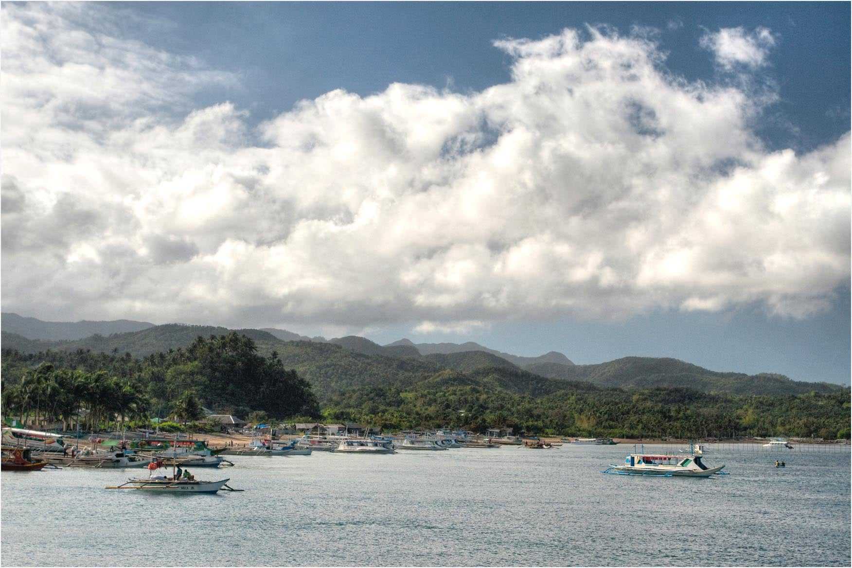 Outrigger boats moored off Caticlan's jetty port with the hills of Aklan behind