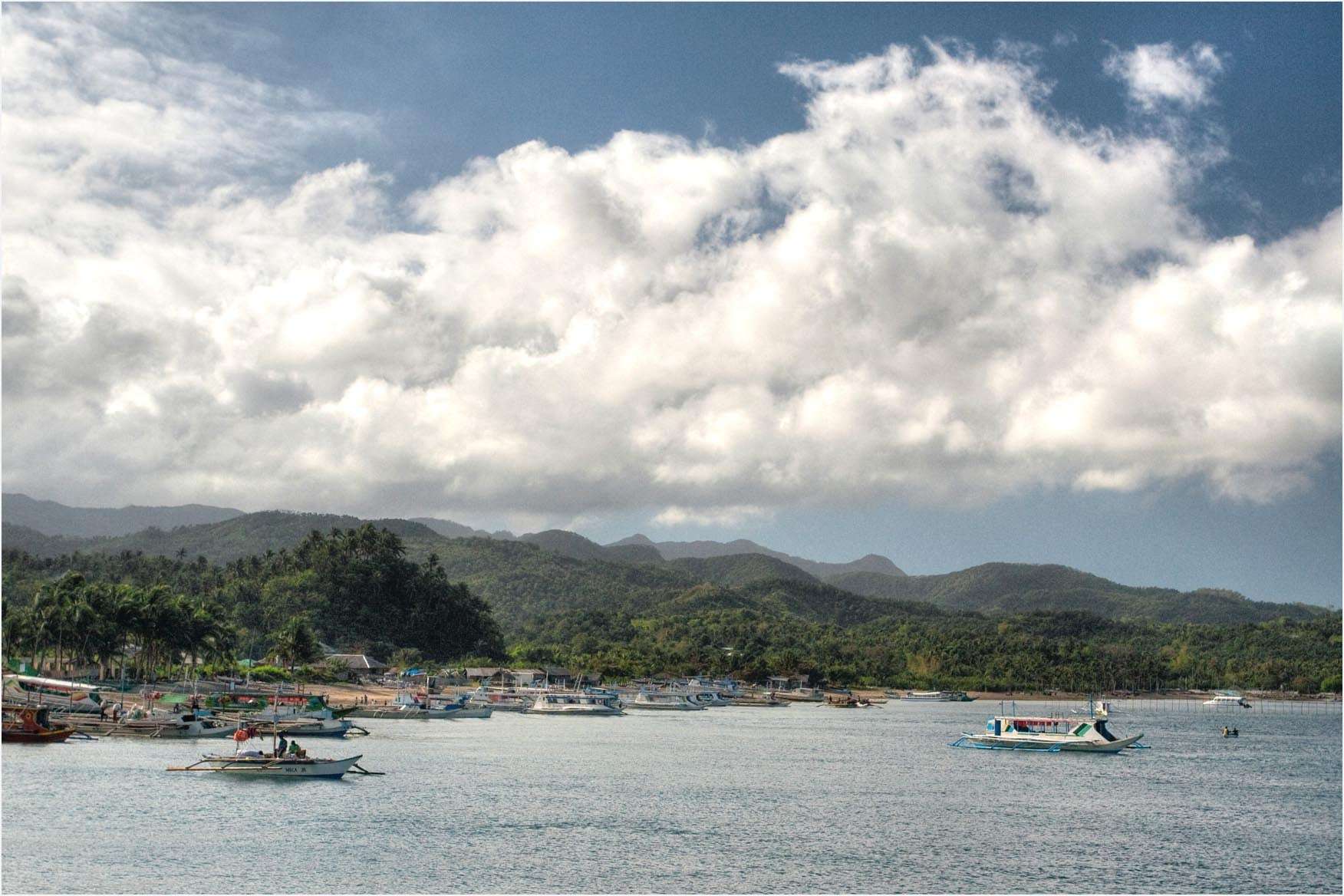 Outrigger boats moored off Caticlan's jetty port with the hills of Aklan behind