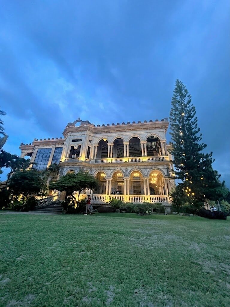 The Ruins Talisay Bacolod Italianate mansion ruins illuminated at twilight with arched colonnade and grand staircase against blue evening sky