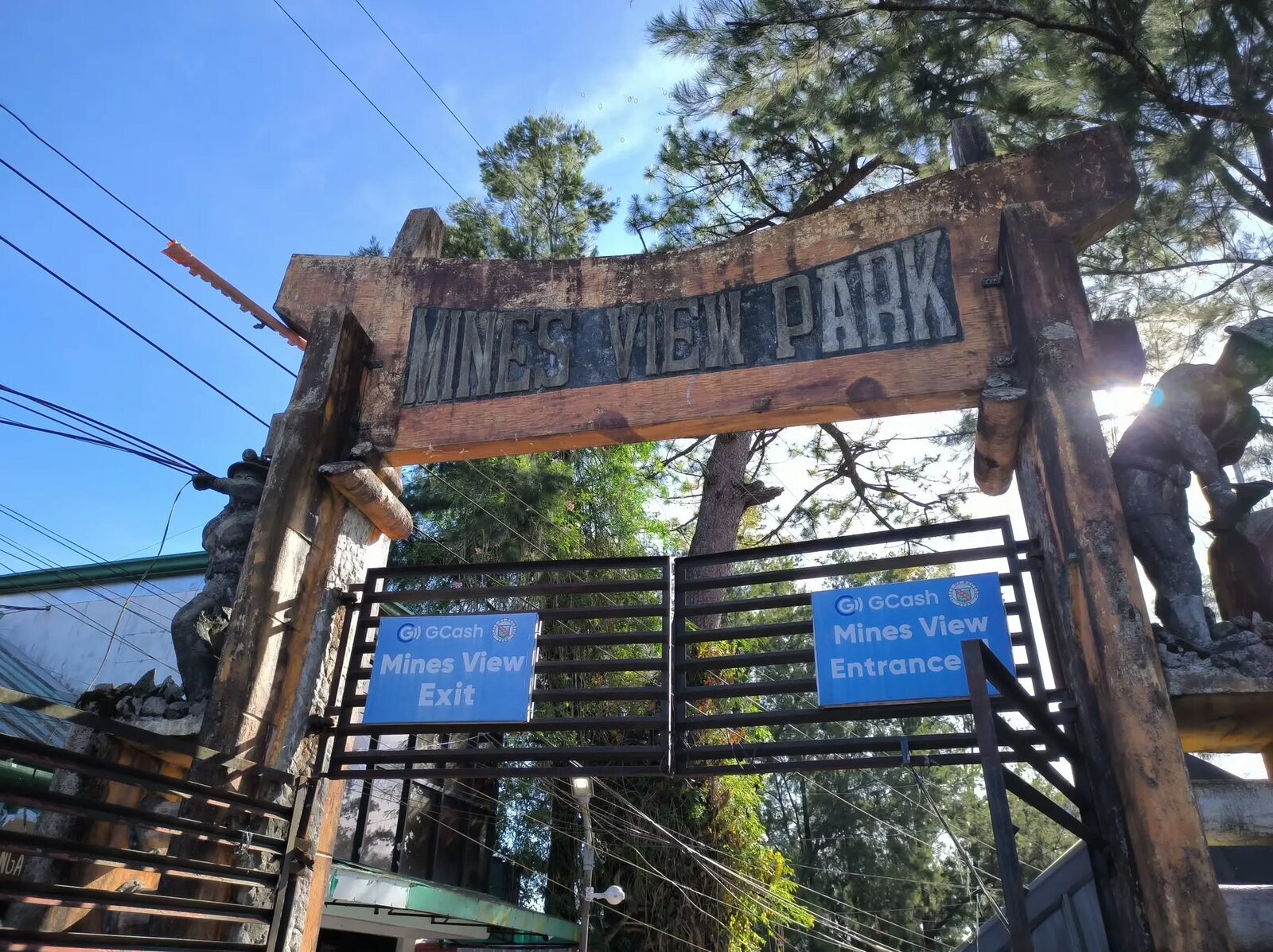 Mines View Park Baguio entrance gate with weathered wooden sign and pine trees in the background