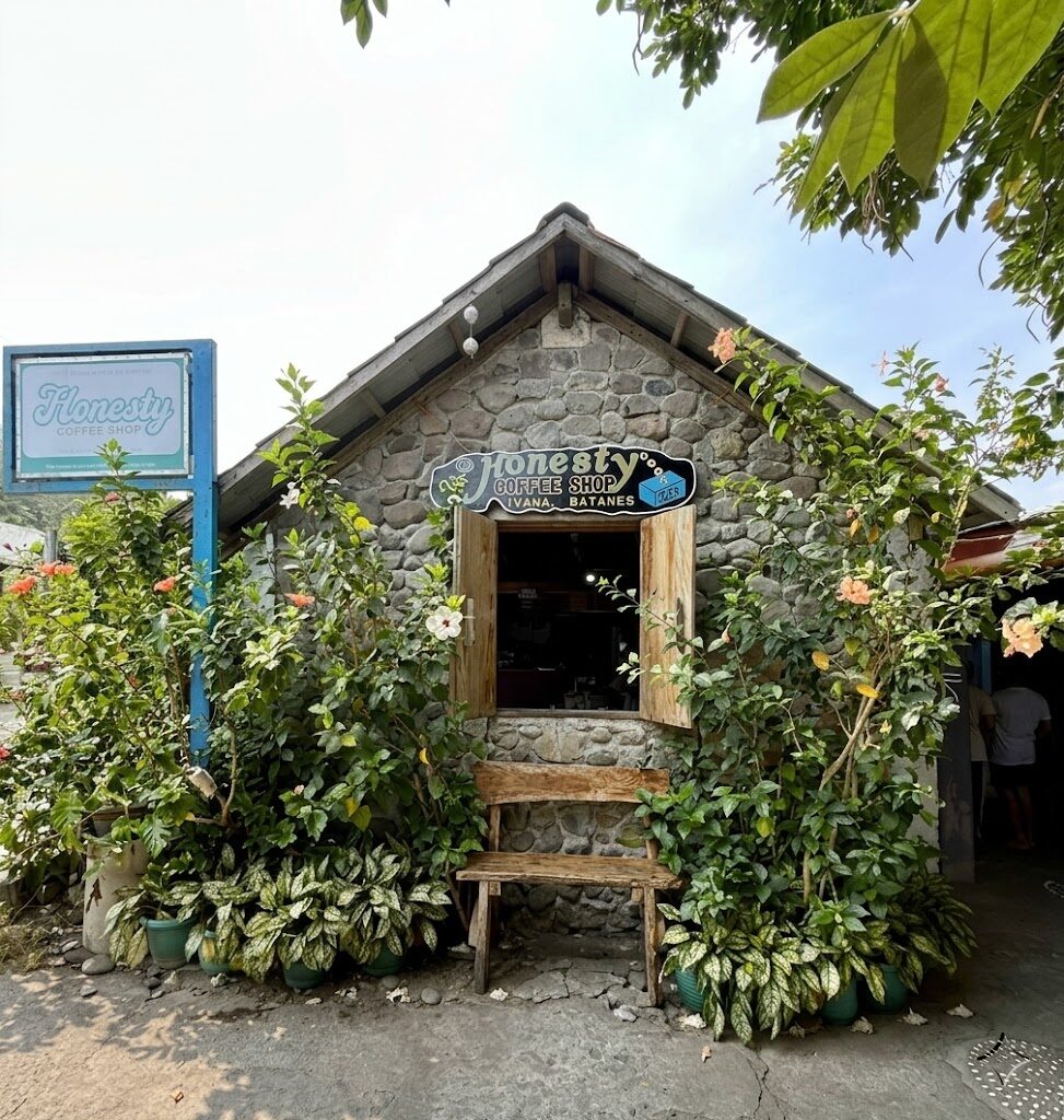 Honesty Coffee Shop Ivana Batanes traditional Ivatan stone bahay-na-bato building with flowering hibiscus plants