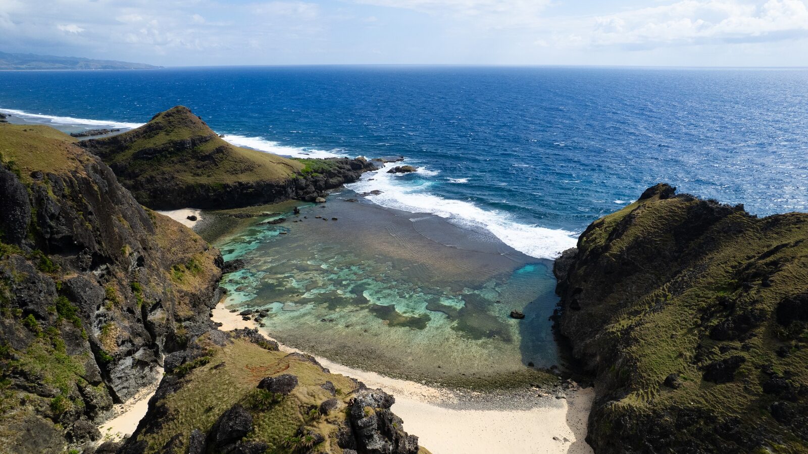 Aerial of Sabtang Island Batanes dramatic karst cliffs and hidden white sand cove on the Pacific Ocean