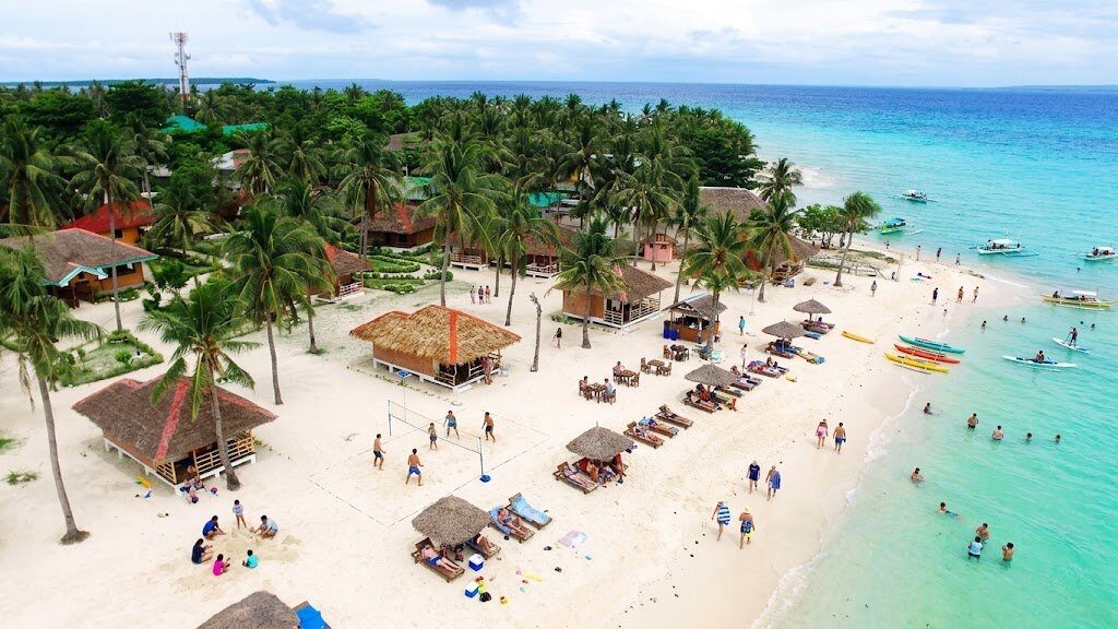 Aerial view of Bantayan Island Sugar Beach with palm trees beach huts and turquoise water in Cebu Philippines
