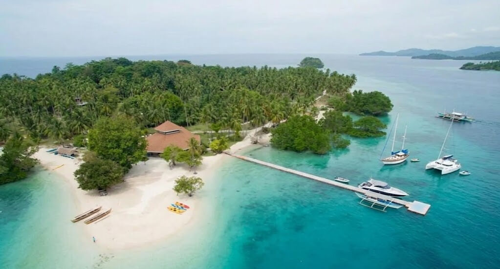 Aerial view of Samal Island near Davao with white sand beach palm trees and boats in clear turquoise water
