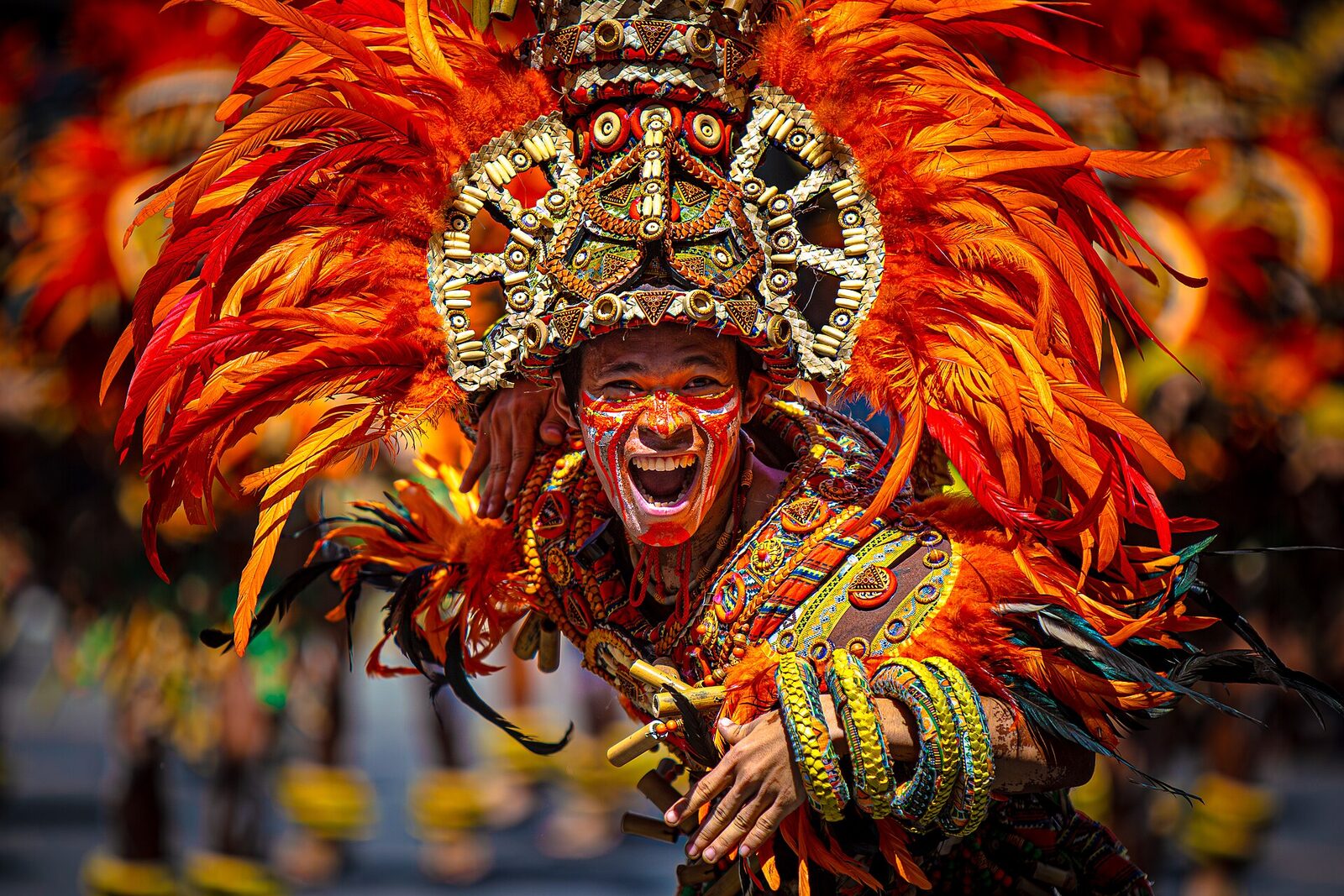 Dinagyang Festival Iloilo Ati tribe warrior performer in elaborate orange feathered headdress and traditional war paint at the annual January parade