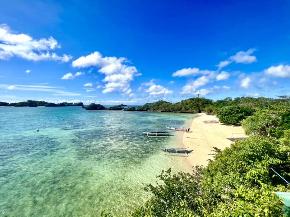 Guimaras Island day trip from Iloilo white sand cove with bangka outrigger boats turquoise water and tropical green islands in the distance