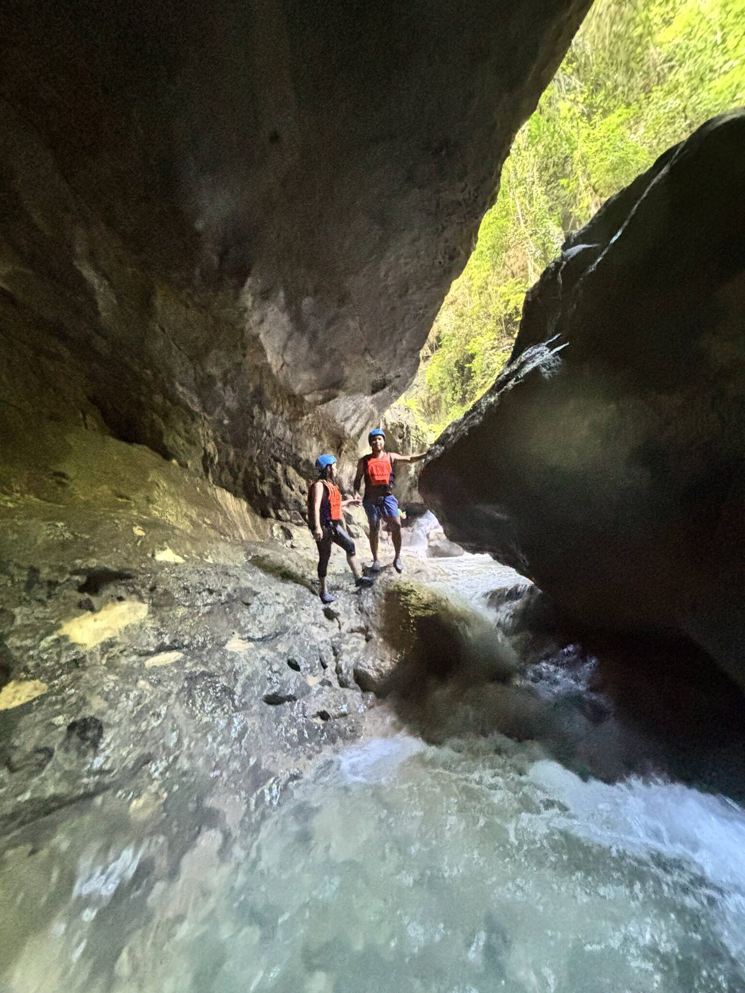 Kawasan Falls canyoneering Cebu two adventurers in helmets and life jackets standing on rocks in a narrow canyon stream