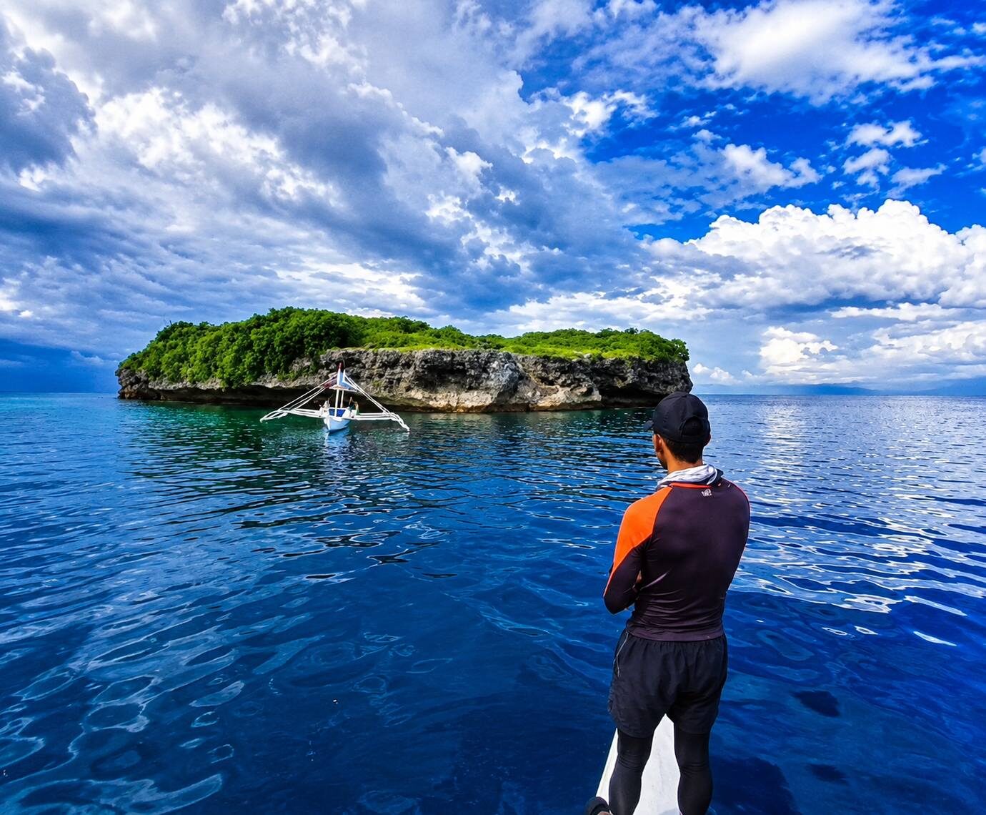 Pescador Island Moalboal Cebu small limestone islet with green vegetation and outrigger boat in deep blue water