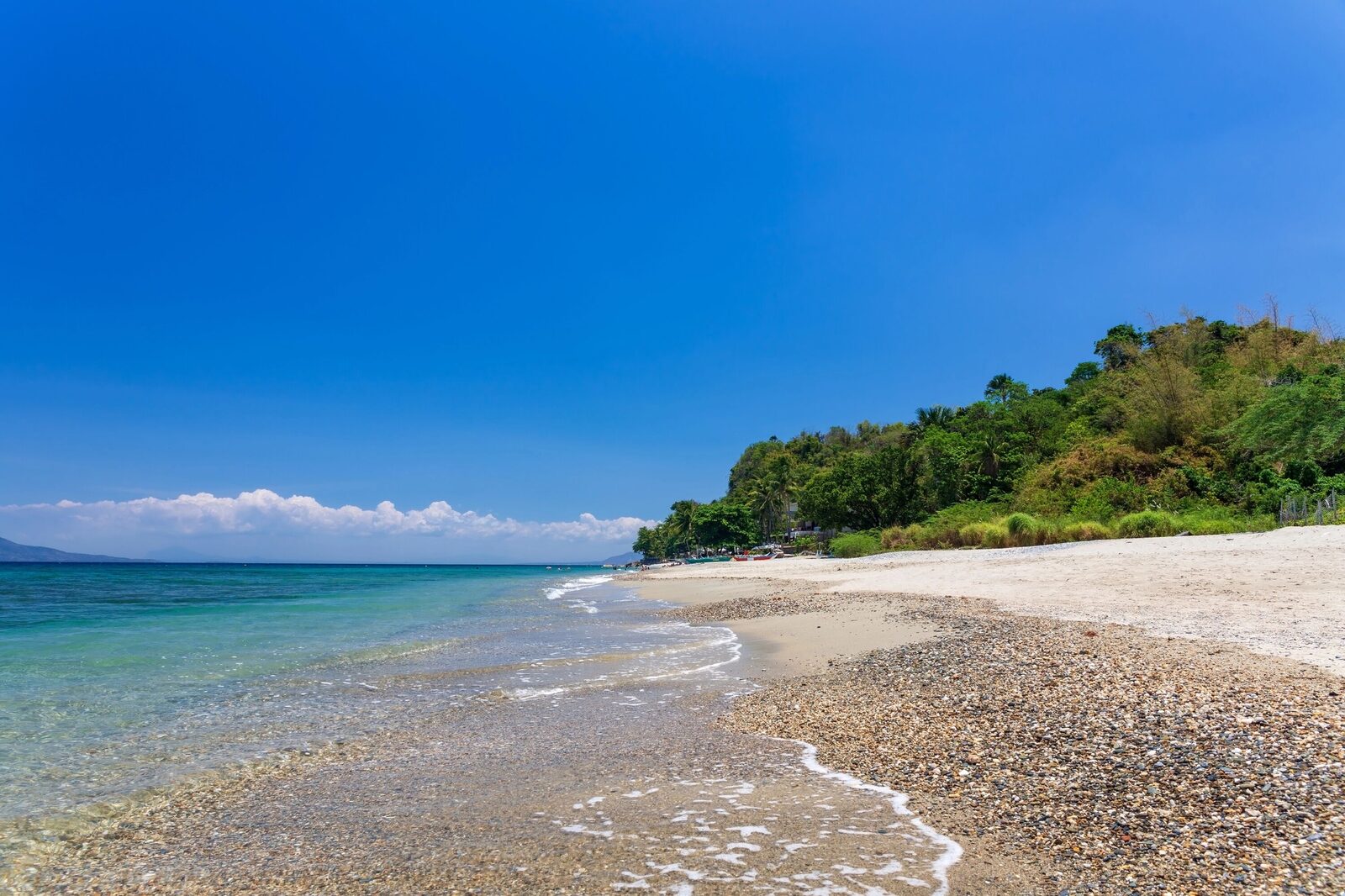Aninuan Beach Puerto Galera quiet white sand beach with clear shallow water and green hillside, a peaceful alternative to White Beach in Mindoro
