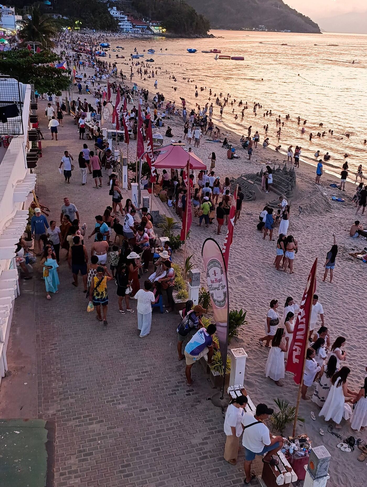 White Beach Puerto Galera busy sunset scene with crowds on the sand, beach activities, and golden sea reflections in Mindoro Philippines