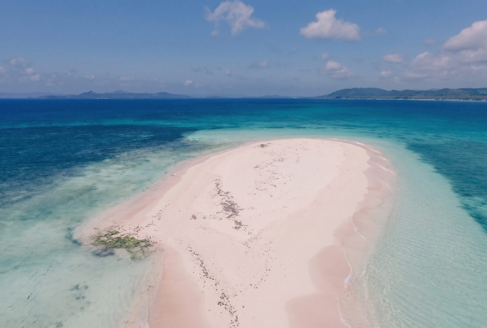 Aerial view of Naked Island Siargao long white sandbar with pink-tinged sand surrounded by turquoise ocean