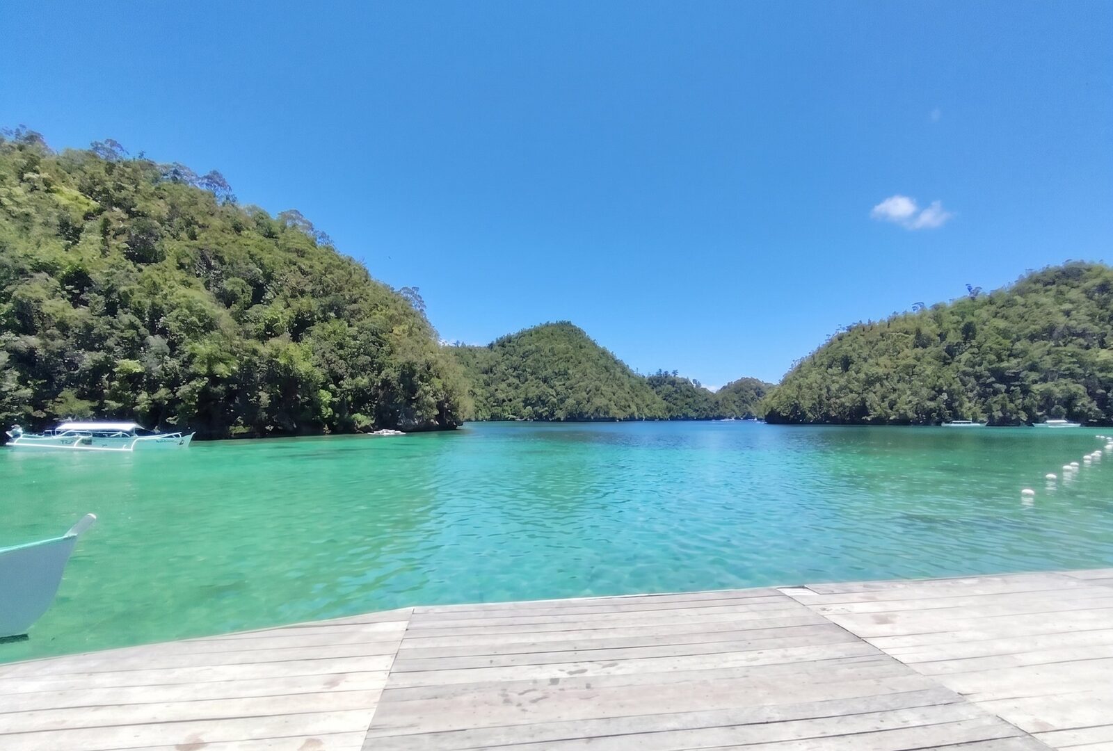 Sugba Lagoon Siargao turquoise water surrounded by jungle-covered hills with wooden deck and outrigger boats