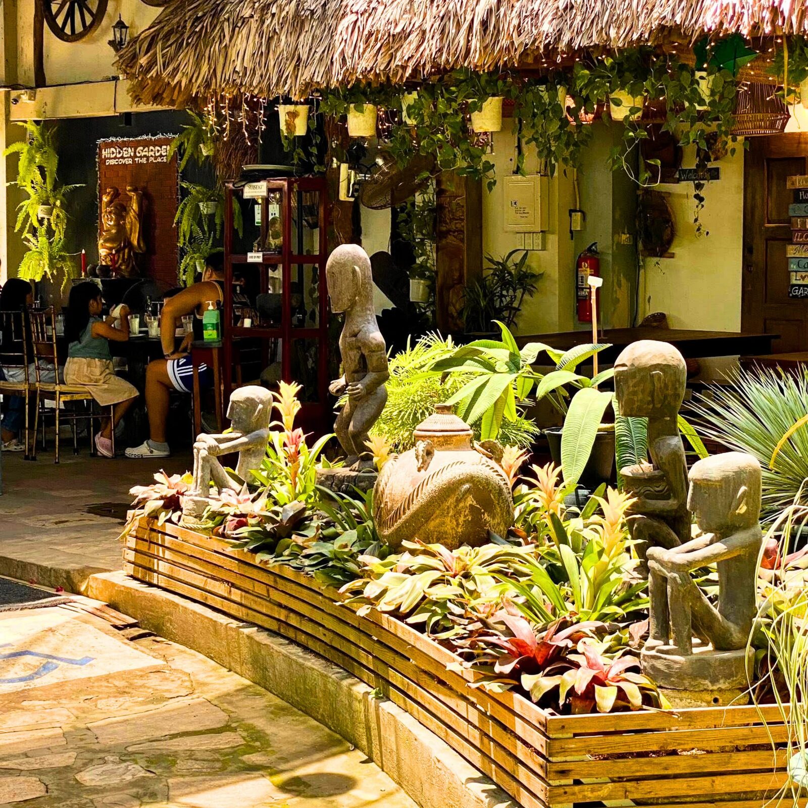 Hidden Garden restaurant Vigan thatched-roof bahay kubo dining area surrounded by tropical plants and Ifugao statues